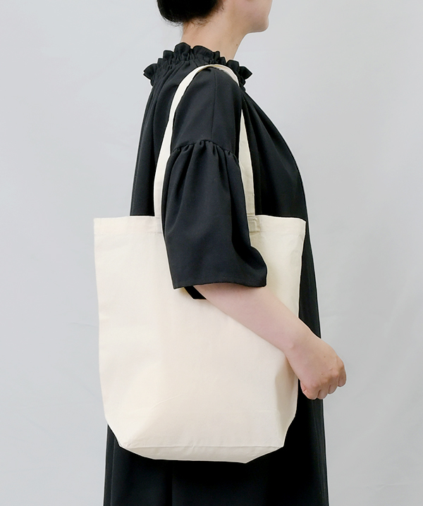オーガニック厚手コットンバッグ(M)を肩にかけた使用イメージ