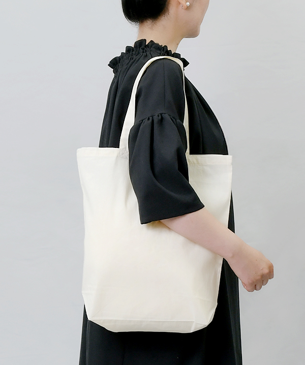 コットンバッグ(M)を肩にかけた使用イメージ